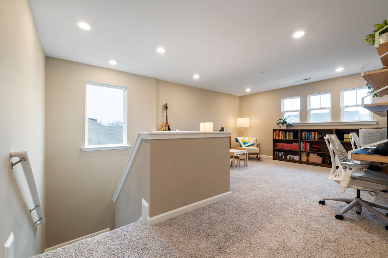 Bright, modern home office space with a cozy ambiance, complete with bookshelves, desk, and natural light.